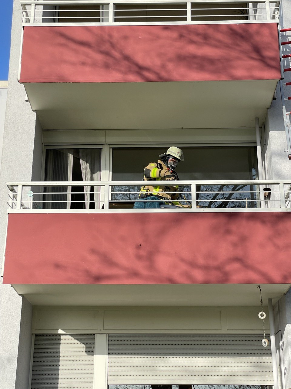 Zu sehen sind ein Balkon und ein Feuerwehrmann