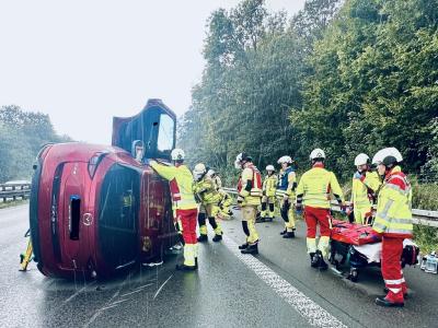 Feuerwehrleute sichern den umgekippten PKW auf der A61