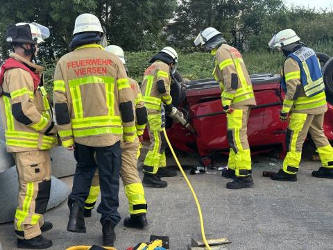 Mehrere Feuerwehrleute arbeiten an einem PKW, der auf dem Dach liegt. Dabei wir der Rettungsspreizer eingesetzt