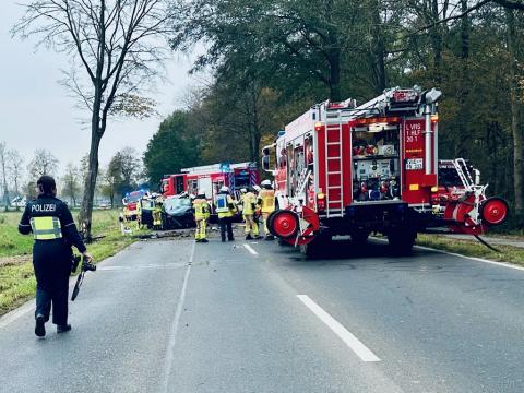 Das Foto von der Einsatzstelle zeigt mehrere Feuerwehrfahrzeuge, Feuerwehrleute, Polizisten und das Unfallfahrzeug 